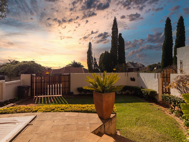 A private rear garden featuring a paved patio area, a swimming pool with a cover, and secure boundary walls with electric fencing.