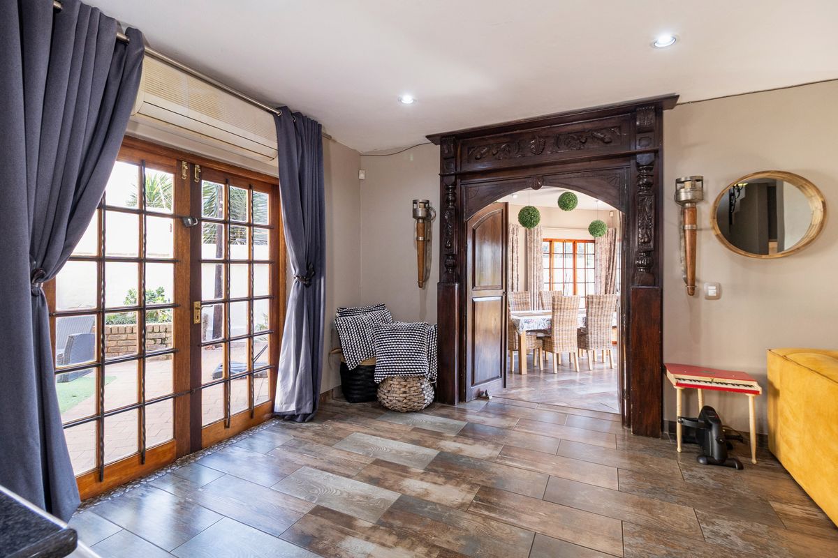 Living area featuring tiled flooring, an ornate wooden archway leading to the dining room, and wooden french doors opening to the patio.