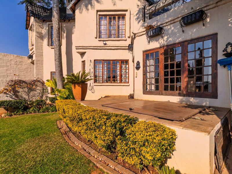 Rear exterior view of the duet property featuring a tiled patio, wooden framed windows and doors, and a landscaped garden area.