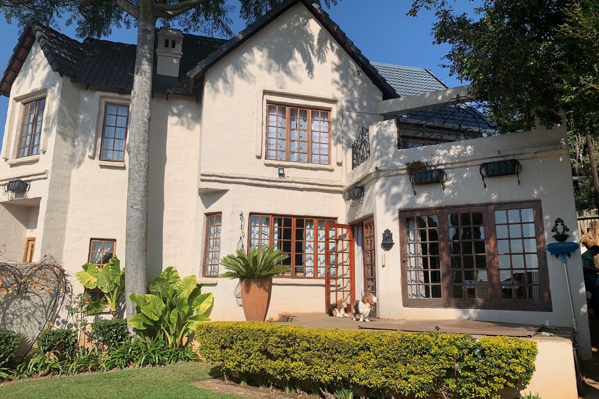 Rear elevation of a two-story duet property featuring a raised patio, timber-framed windows, and a well-maintained garden area.