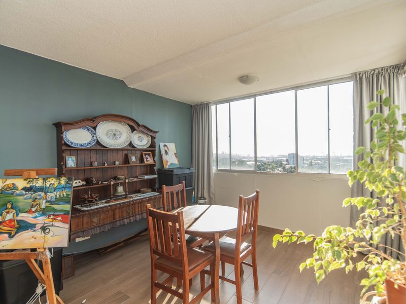 A bright dining area featuring large sliding windows with expansive city views and durable laminate flooring.