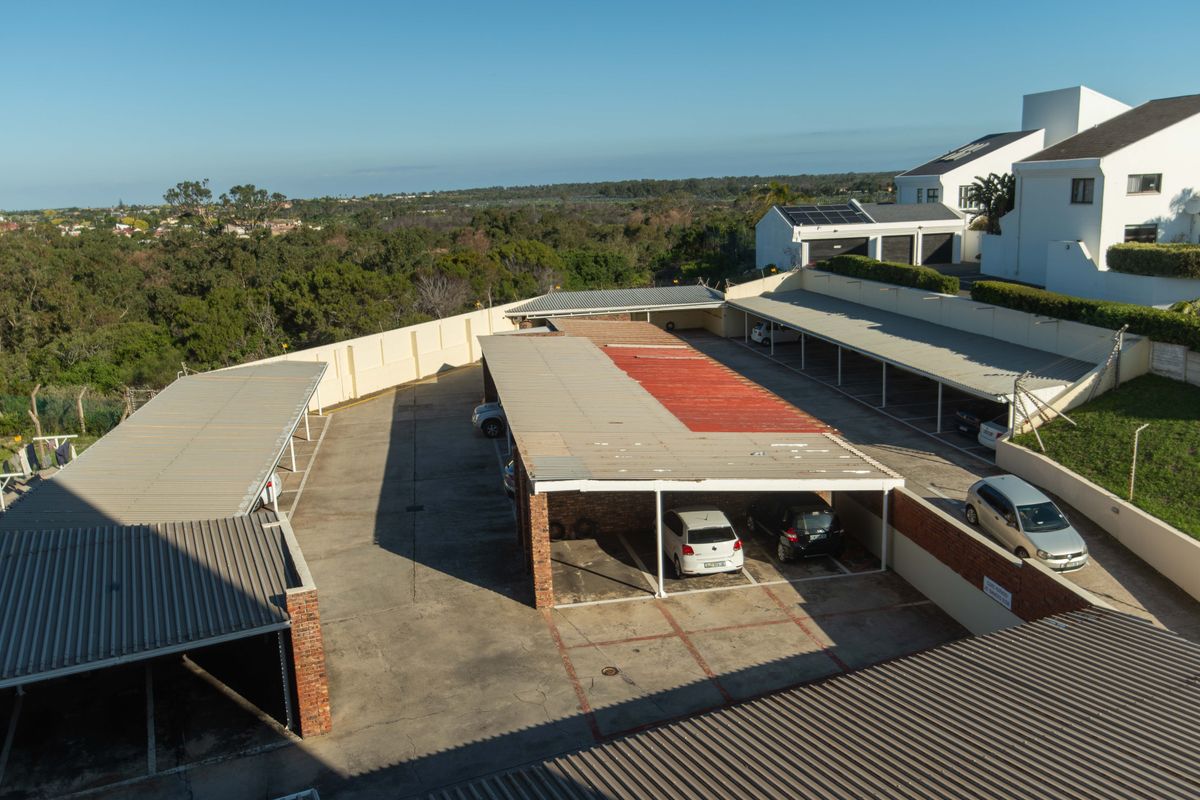 Aerial view of the apartment complex parking area featuring multiple covered carports and concrete paving.
