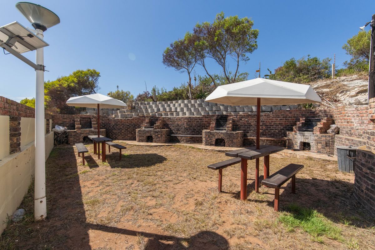 Outdoor communal area featuring multiple built-in brick braai stations, a retaining wall, and a grassed yard space.