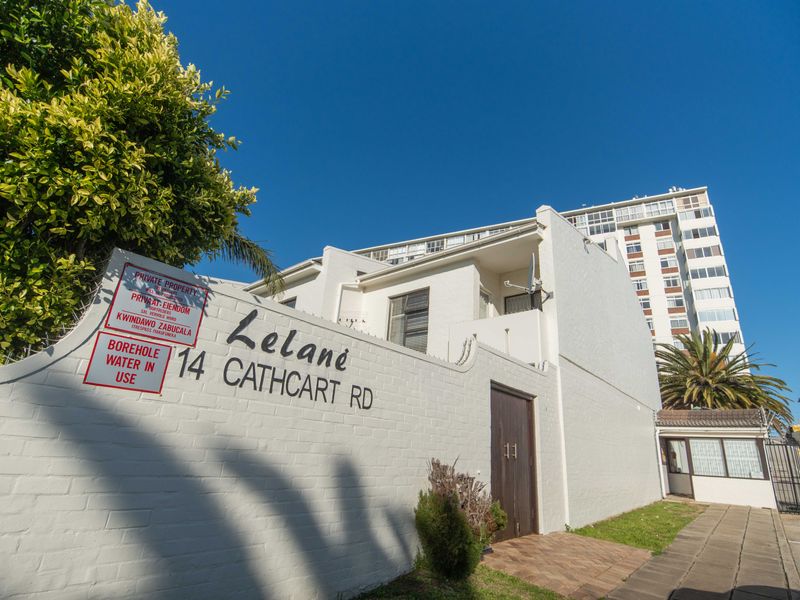 Front exterior view of the Lelane apartment complex, featuring a white boundary wall, secure entrance gate, and paved pedestrian access.