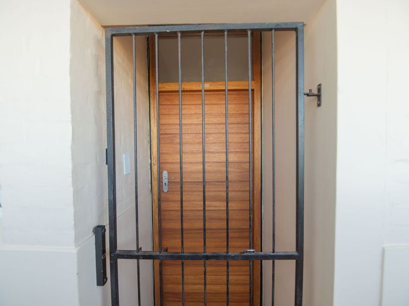 A secure apartment entrance featuring a sturdy metal security gate and a solid wooden door.