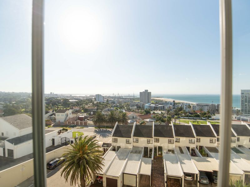 Elevated coastal and urban view overlooking residential townhouses, surrounding neighborhood, and the distant ocean horizon.