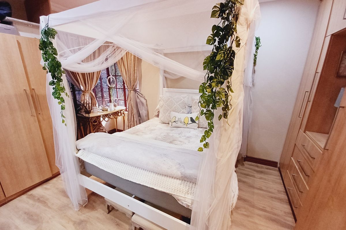 A cozy bedroom featuring light wood-tone built-in cupboards and durable laminate flooring, creating a warm and functional living space.