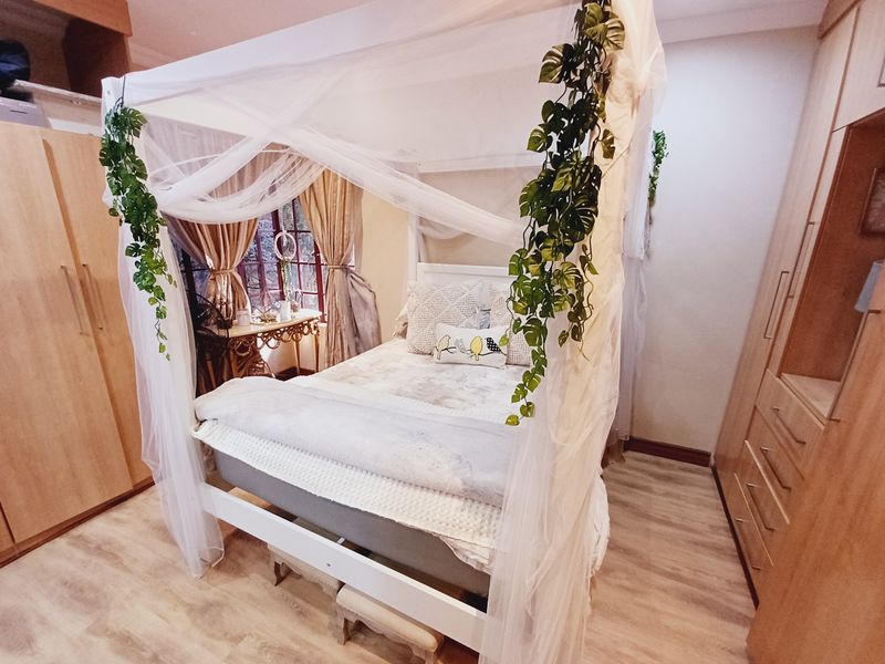 A cozy bedroom featuring light wood-tone built-in cupboards and durable laminate flooring, creating a warm and functional living space.