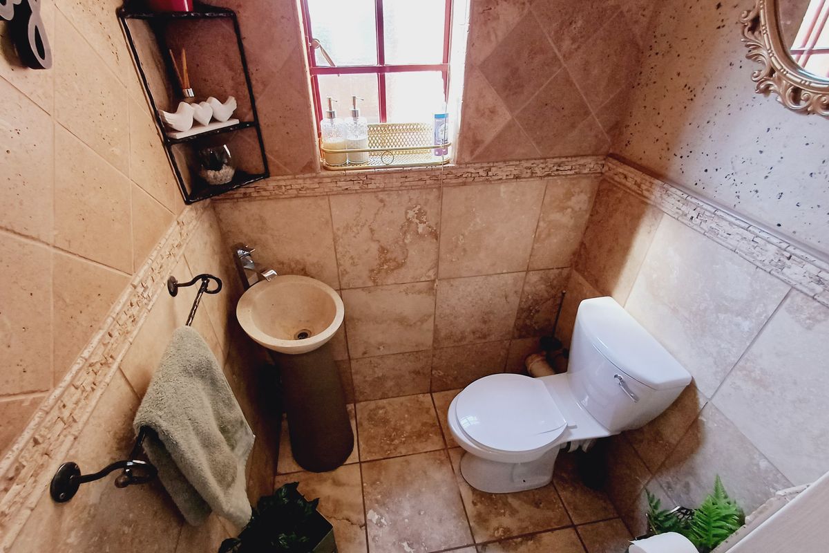 Compact guest bathroom featuring a pedestal basin, toilet, and full-height natural stone-style wall tiling.