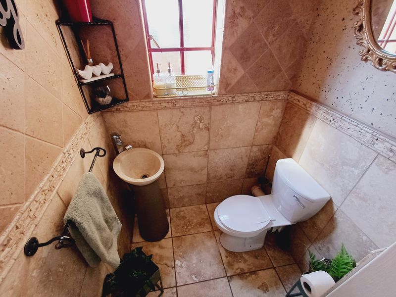 Compact guest bathroom featuring a pedestal basin, toilet, and full-height natural stone-style wall tiling.