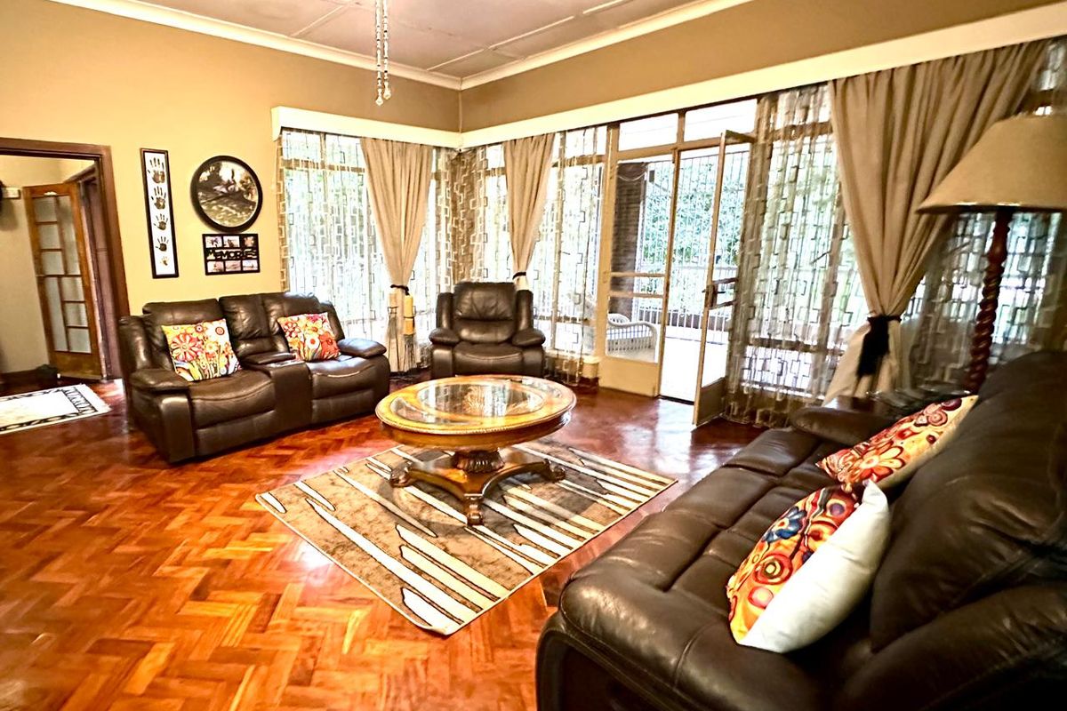 Spacious living room featuring traditional parquet flooring, a ceiling fan, and large glass sliding doors providing access to the outdoor area.
