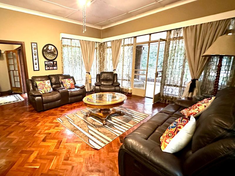 Spacious living room featuring traditional parquet flooring, a ceiling fan, and large glass sliding doors providing access to the outdoor area.