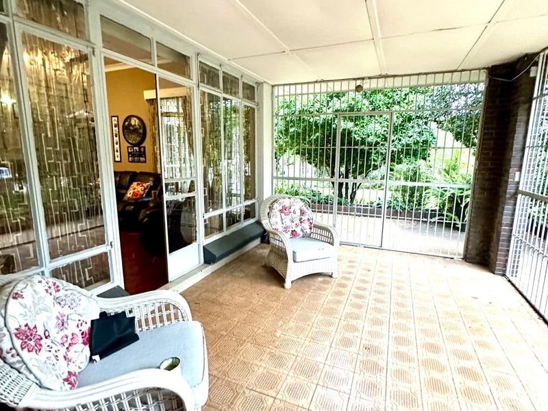 A covered patio area featuring tiled flooring, secure metal gates, and large glass sliding doors providing access to the interior living space.