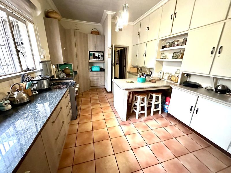 A functional kitchen featuring extensive built-in cabinetry, granite countertops, a breakfast nook, and ceramic floor tiles.
