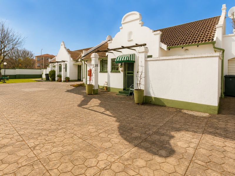 A well-maintained retirement village unit featuring a paved driveway, gabled architectural details, and secure entrance with an awning.