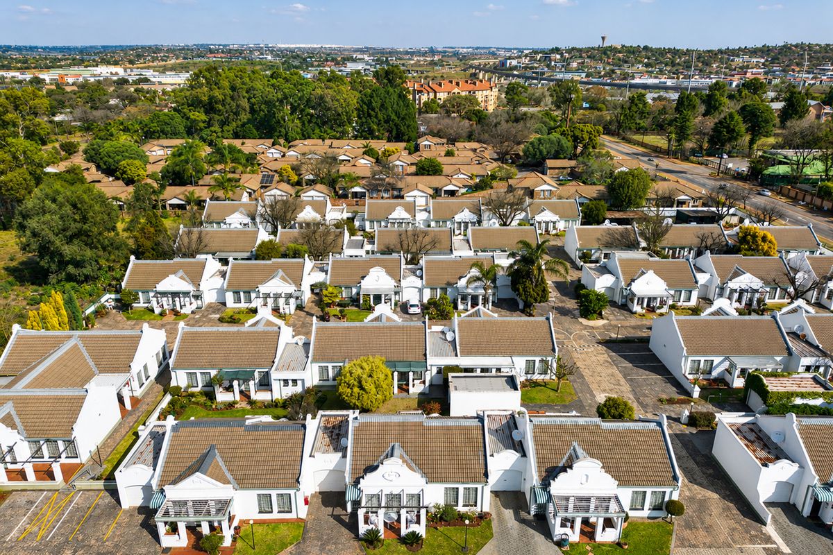 Aerial view of a well-maintained retirement village featuring multiple residential units with tiled roofs, paved driveways, and established garden areas.