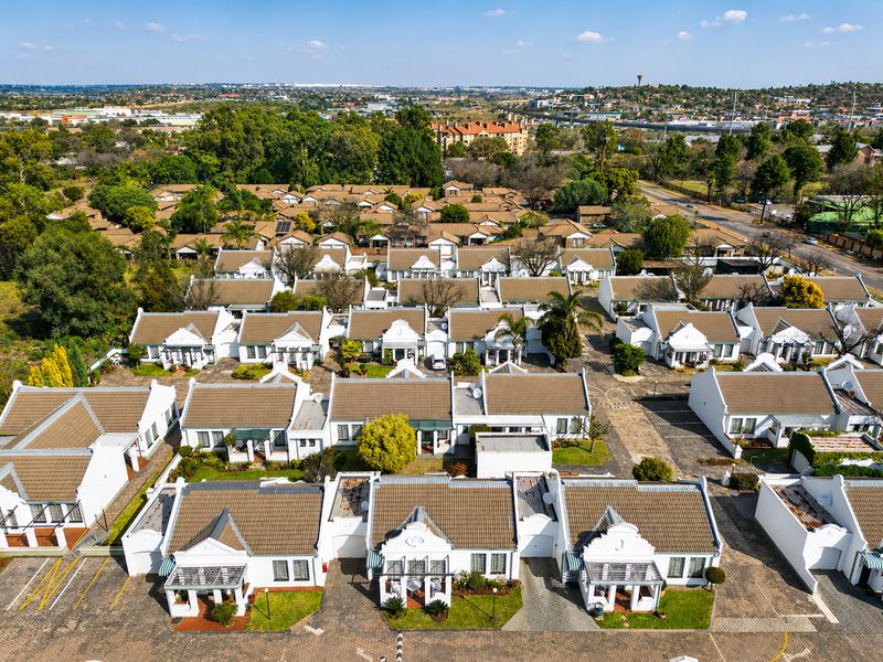 Aerial view of a well-maintained retirement village featuring multiple residential units with tiled roofs, paved driveways, and established garden areas.