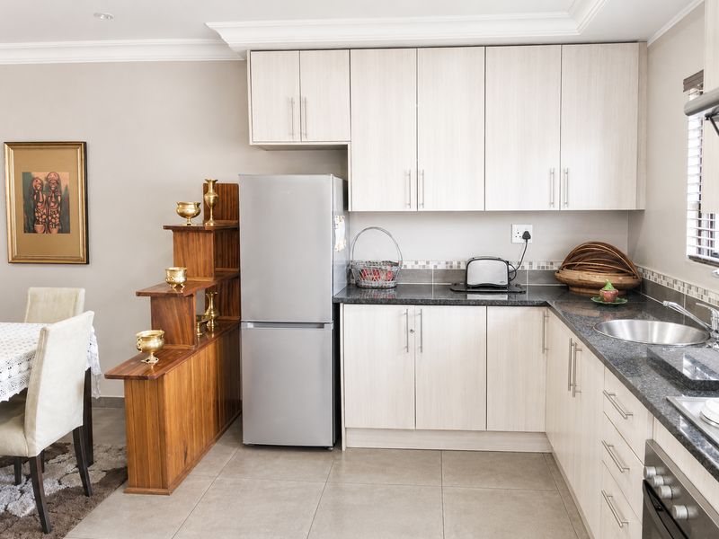 A well-maintained kitchen featuring light wood-finish cabinetry, granite countertops, a mosaic tile backsplash, and integrated stainless steel appliances.