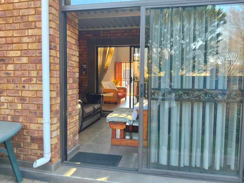 A covered patio area featuring brick walls and tiled flooring, providing a transition space between the outdoor area and the interior living room.