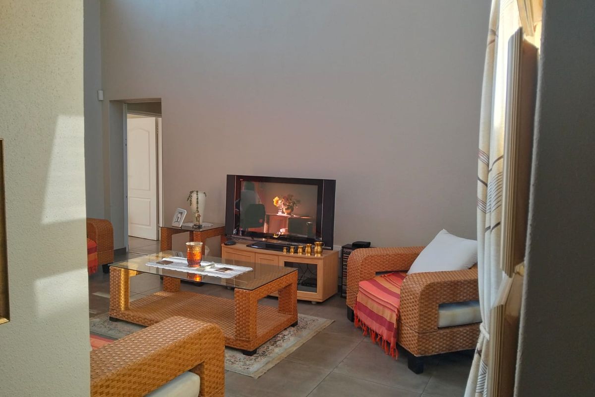 A living room area featuring tiled flooring and high ceilings, providing a spacious feel with natural light.