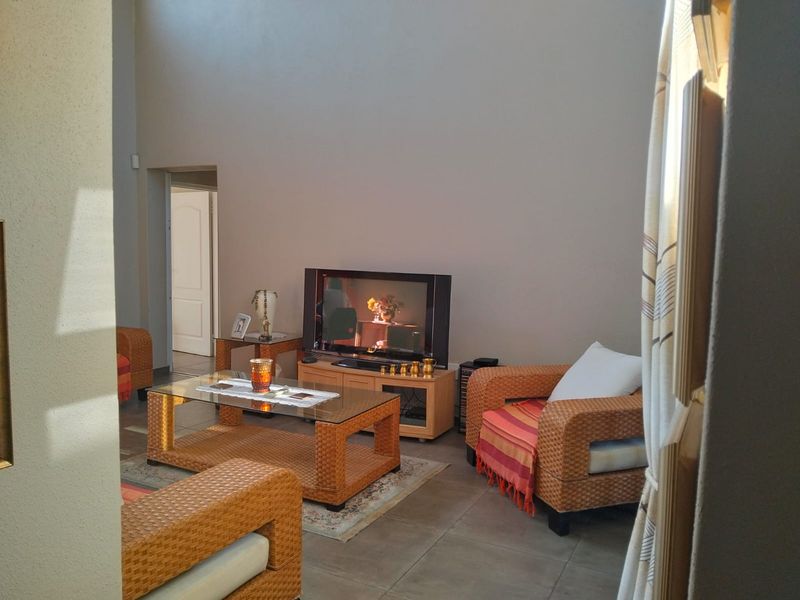A living room area featuring tiled flooring and high ceilings, providing a spacious feel with natural light.