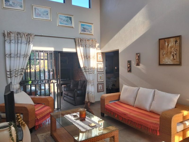 Spacious living room featuring high ceilings, tiled flooring, and a sliding glass door with security gate leading to an outdoor area.