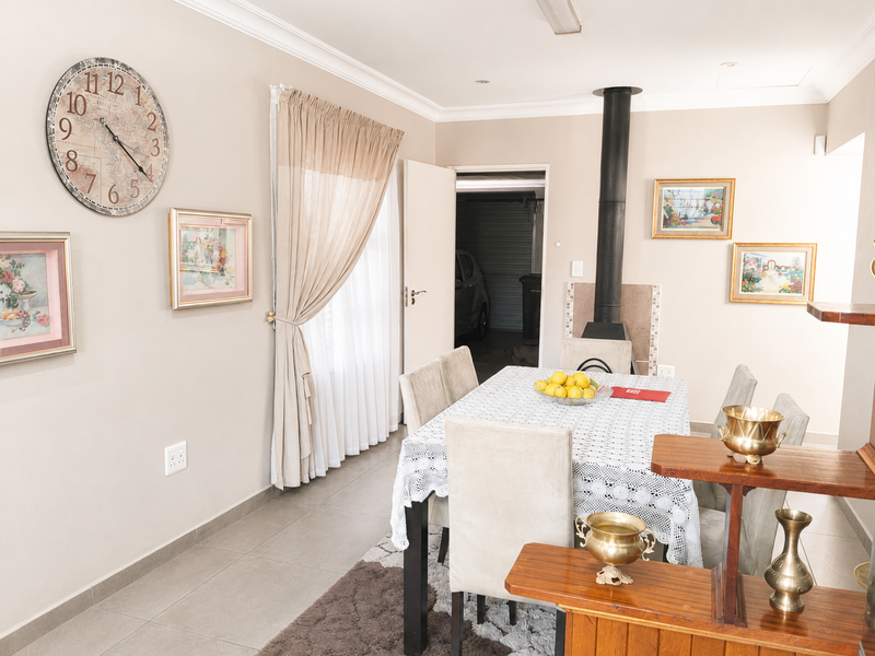 A well-maintained dining area featuring tiled flooring, coved cornicing, and a modern freestanding fireplace, providing a comfortable space for meals.