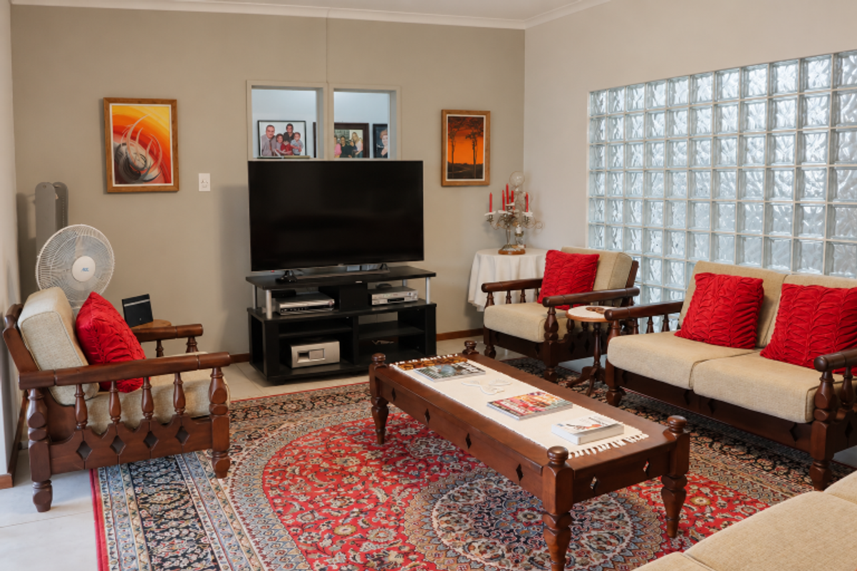 A living room featuring a distinctive glass block wall, tiled flooring, and coved ceiling details, providing a bright and functional space.