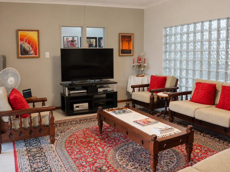 A living room featuring a distinctive glass block wall, tiled flooring, and coved ceiling details, providing a bright and functional space.