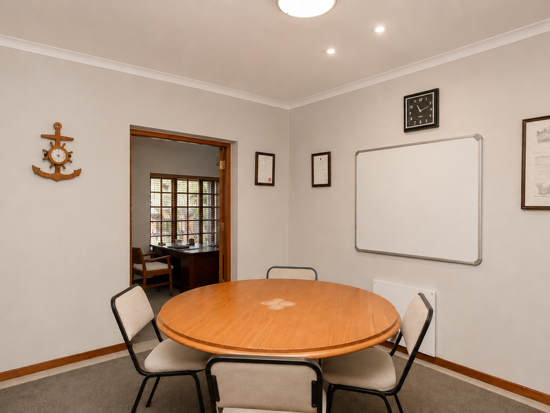A functional office space featuring neutral walls, carpeted flooring, and recessed lighting, providing a clean and professional environment for work or study.