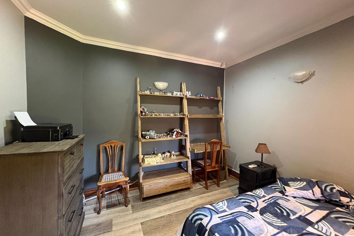 A bedroom featuring dark accent walls, crown molding, recessed lighting, and durable laminate flooring.