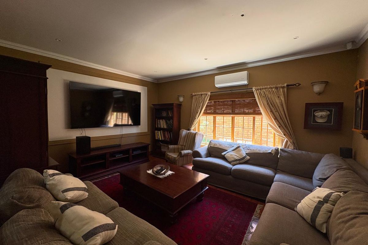A comfortable living room featuring recessed downlighting, wall-mounted air conditioning, and timber-framed windows, providing a cozy and functional space for relaxation.