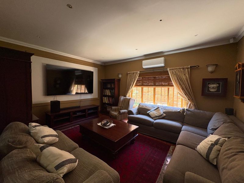 A comfortable living room featuring recessed downlighting, wall-mounted air conditioning, and timber-framed windows, providing a cozy and functional space for relaxation.