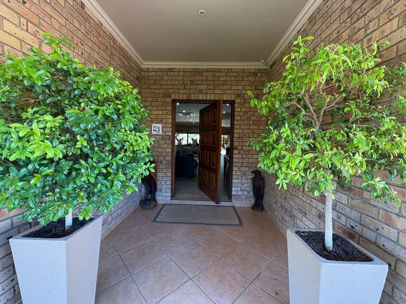 A covered entrance porch featuring exposed brick walls, tiled flooring, and a solid timber front door leading into the home.