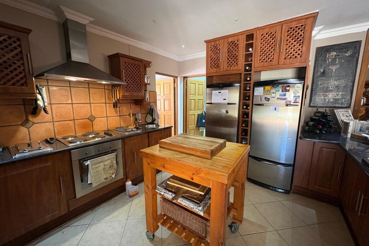 A functional kitchen featuring warm-toned wooden cabinetry, granite countertops, a tiled backsplash, and integrated stainless steel appliances.