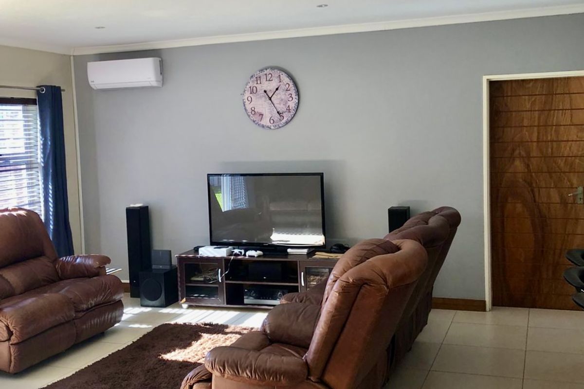 A comfortable living room featuring tiled flooring, recessed downlighting, and a wall-mounted air conditioning unit.