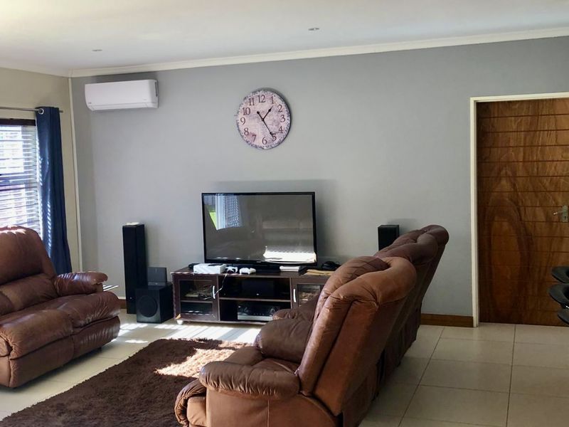 A comfortable living room featuring tiled flooring, recessed downlighting, and a wall-mounted air conditioning unit.
