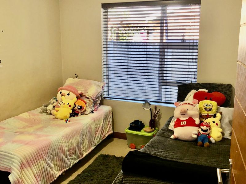 A functional bedroom featuring carpeted flooring, a window with venetian blinds, and a curtain rod, providing a comfortable space for rest.