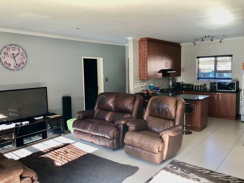 Open-plan living area featuring a kitchen with dark wood cabinetry, granite countertops, and tiled flooring, seamlessly flowing into the lounge space.