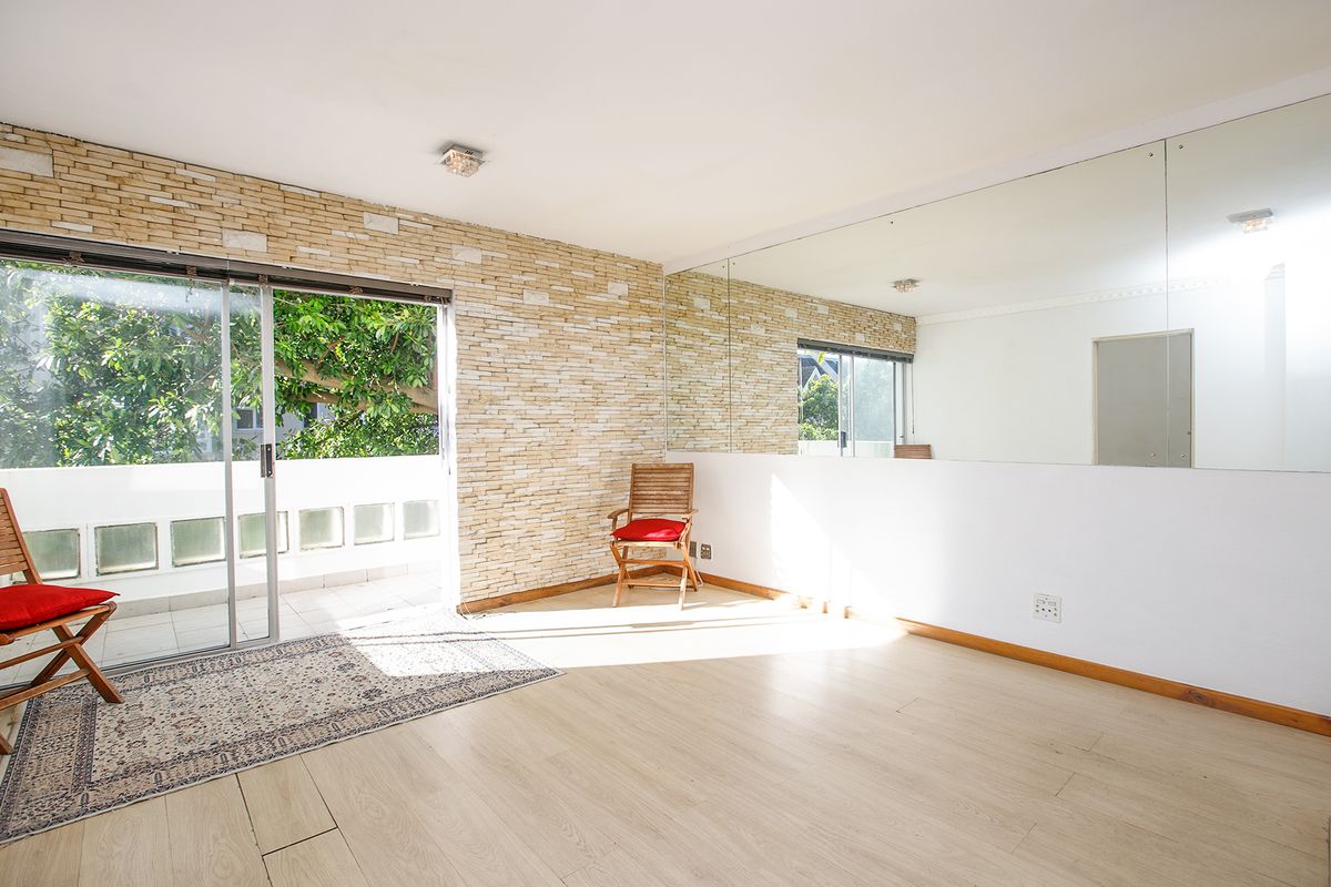 Bright living area featuring a stone veneer accent wall, large wall-mounted mirror, and sliding glass doors leading to an outdoor balcony.