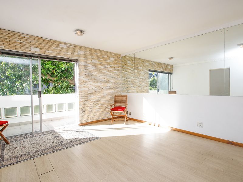 Bright living area featuring a stone veneer accent wall, large wall-mounted mirror, and sliding glass doors leading to an outdoor balcony.
