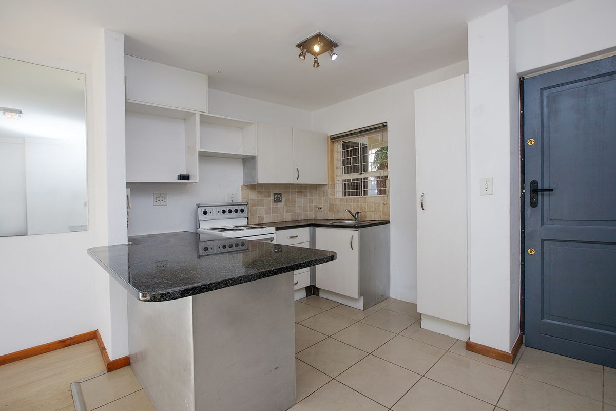 A functional kitchen featuring granite countertops, built-in cabinetry, a tiled backsplash, and a freestanding stove, offering a practical layout for daily use.