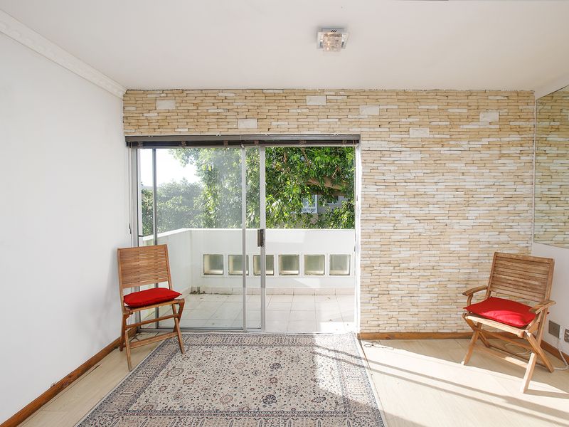 Living room featuring a stone veneer accent wall, laminate flooring, and sliding glass doors providing access to an outdoor balcony area.