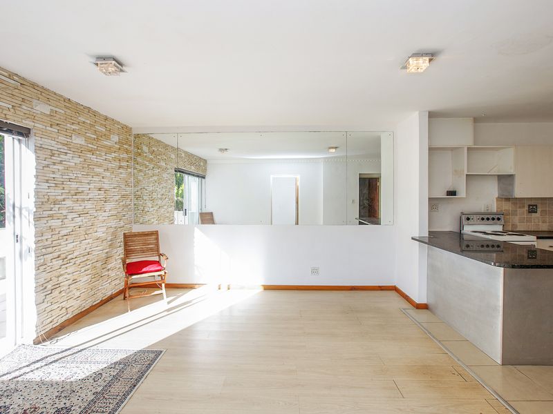 Open-plan living and kitchen area featuring a stone-clad feature wall, granite countertops, and direct access to a balcony through sliding glass doors.