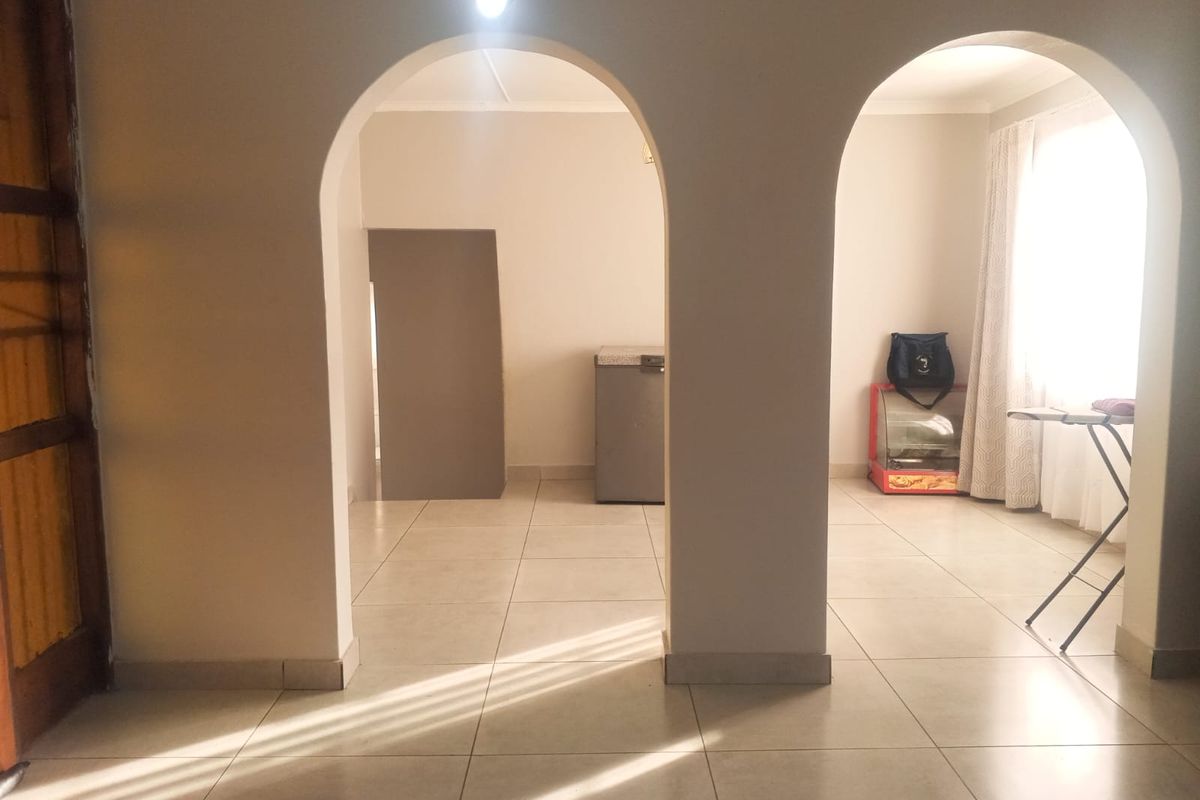 An open-plan living area featuring neutral tiled flooring and distinctive arched architectural doorways, providing a bright and versatile space.