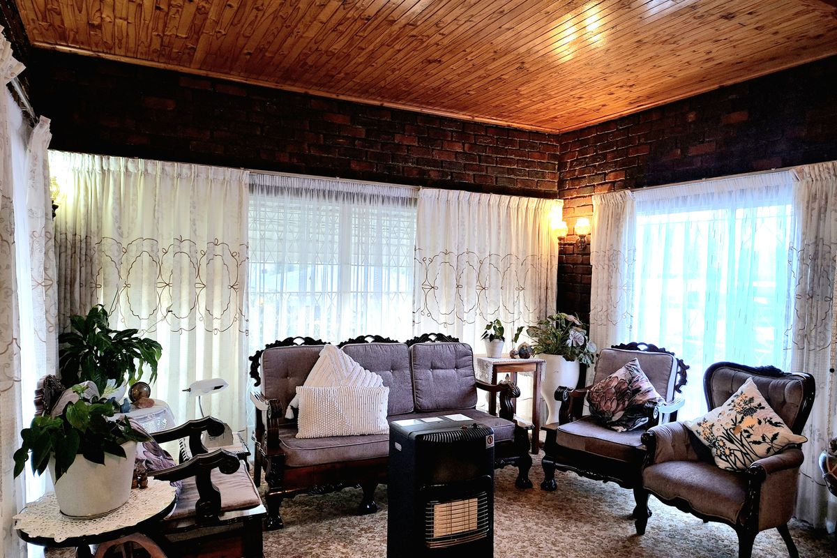 A cozy living room featuring exposed brick walls, a warm timber tongue and groove ceiling, and large sliding glass doors providing ample natural light.