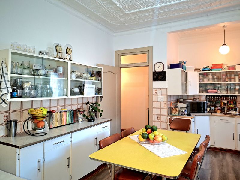 A functional kitchen featuring white cabinetry, tiled backsplash, and a distinctive pressed metal ceiling, offering a classic aesthetic with ample storage space.