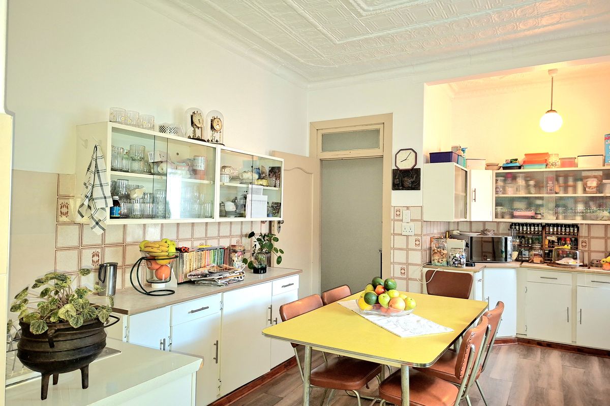 A functional kitchen featuring classic pressed metal ceilings, ample built-in cabinetry, and a tiled backsplash, offering a traditional layout with a dedicated dining area.