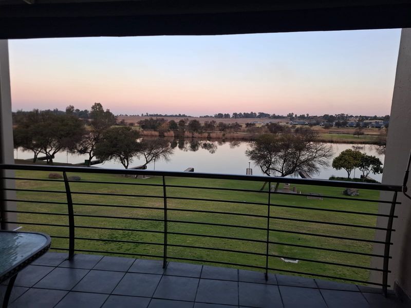A covered balcony featuring tiled flooring and a metal balustrade, offering scenic views of the lake and surrounding landscape.