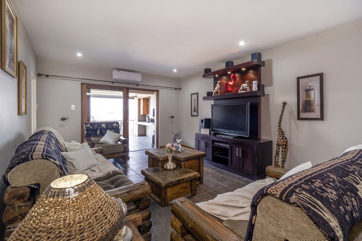 A comfortable living room featuring tiled flooring, a built-in media unit, recessed lighting, and a split-system air conditioner, with access to an outdoor patio area.